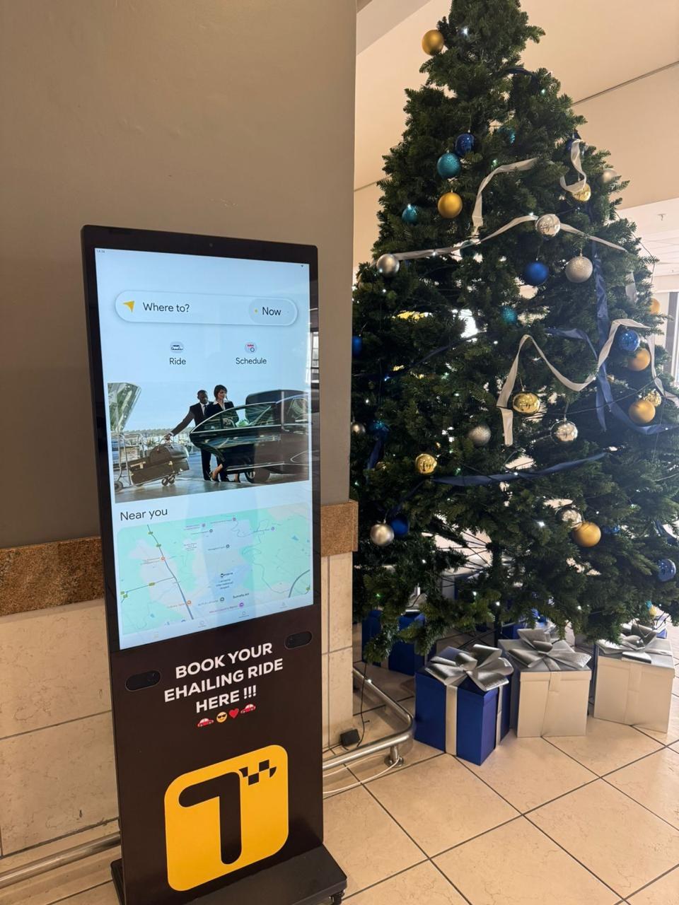 Freestanding indoor LCD display beside a Christmas installation
